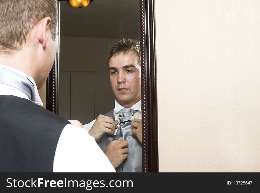 Groom preparing before the wedding, looking in the mirror