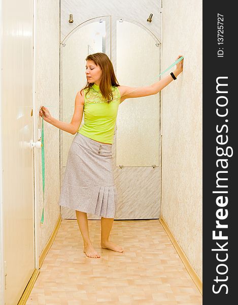 The girl measures width of a corridor in centimetre