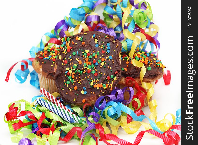 Confetti cupcakes with chocolate frosting surrounded by colorful ribbons and candles. Confetti cupcakes with chocolate frosting surrounded by colorful ribbons and candles