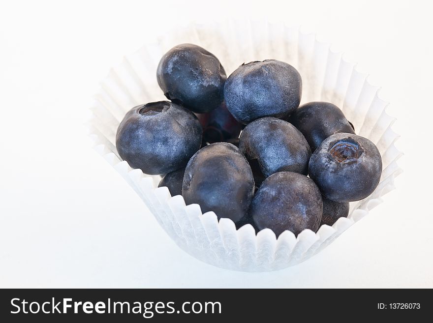 Fresh blueberries in a white paper muffin cup - isolated. Fresh blueberries in a white paper muffin cup - isolated