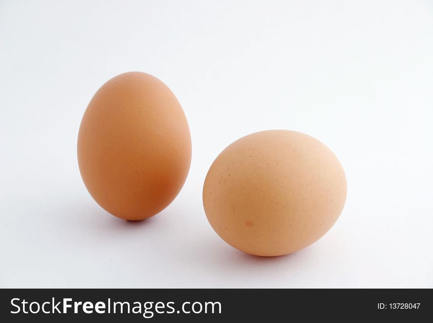 Two eggs with white background, one standing.