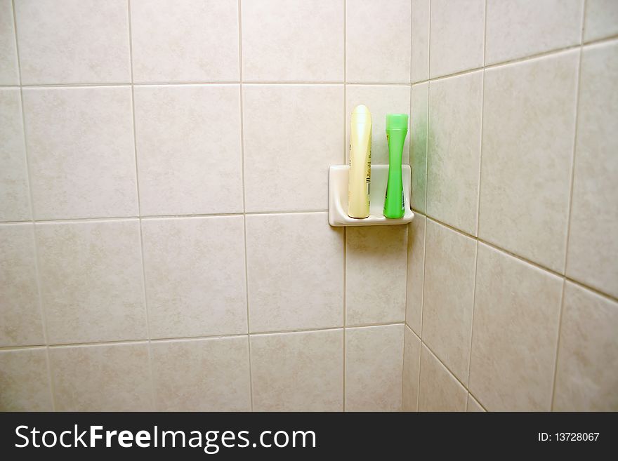 New tile shower space in bathroom with shampoo shelf.