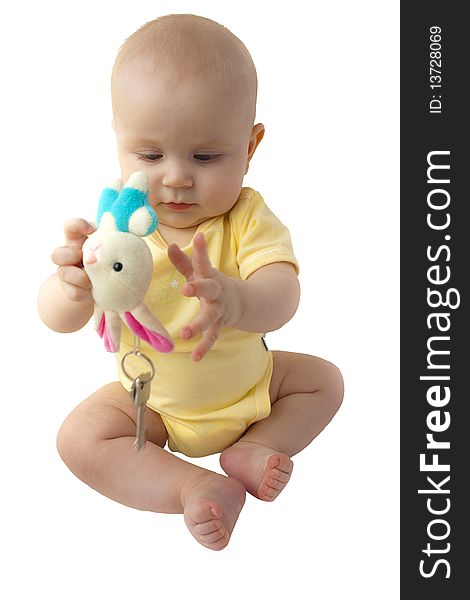 The baby sits in yellow clothes and plays with a toy on which two keys hang