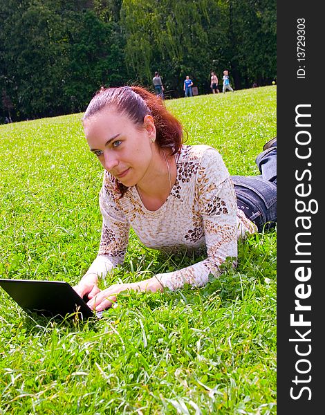 Young girl lying on green grass with laptop. Young girl lying on green grass with laptop