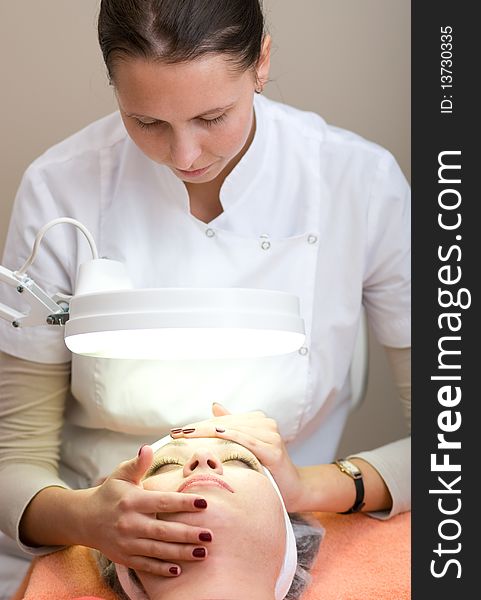 Woman in Cosmetic Cabinet under lamp. Faces skin cleaning.