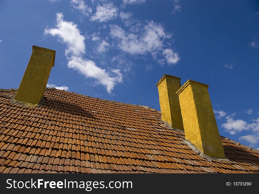 Three chimneys on one rooftop against a blue sky background. Three chimneys on one rooftop against a blue sky background