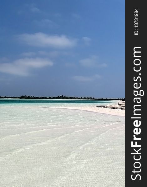 White sand beach with shallow water and turquoise blue color under blue sky and a few clouds. White sand beach with shallow water and turquoise blue color under blue sky and a few clouds