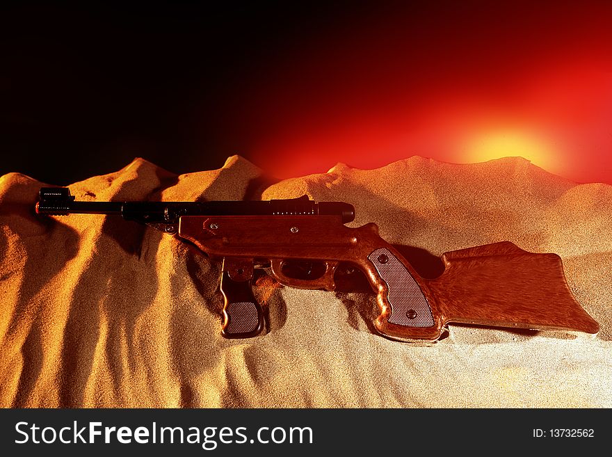 Gun in desert sand with sunrise. Gun in desert sand with sunrise