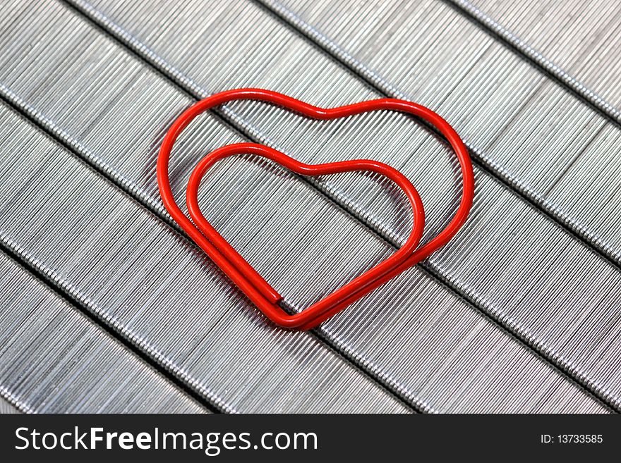 Close up shot of red paper clip over staples background. Close up shot of red paper clip over staples background