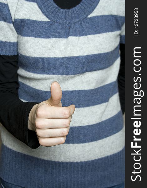 Against the background of a striped vest young white girl's hand with his thumb up. Success. Against the background of a striped vest young white girl's hand with his thumb up. Success