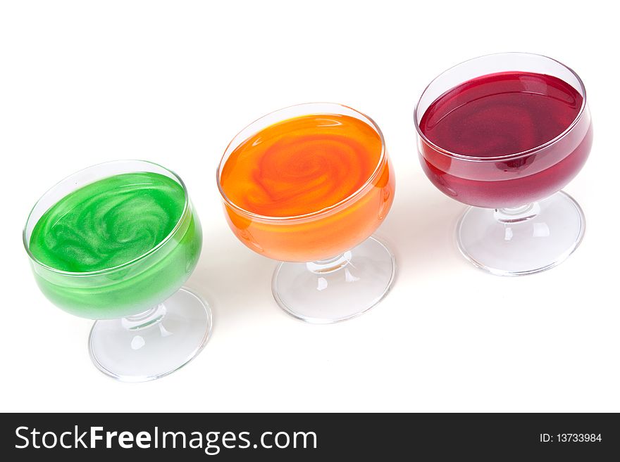 Green, yellow and red jelly in glass on white background
