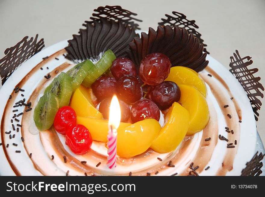 A birthday cake with fruits as topping