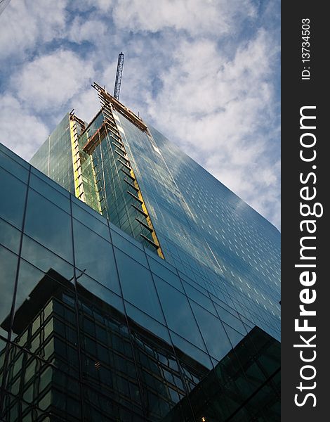 A construction crane high above a glass sckyscraper
