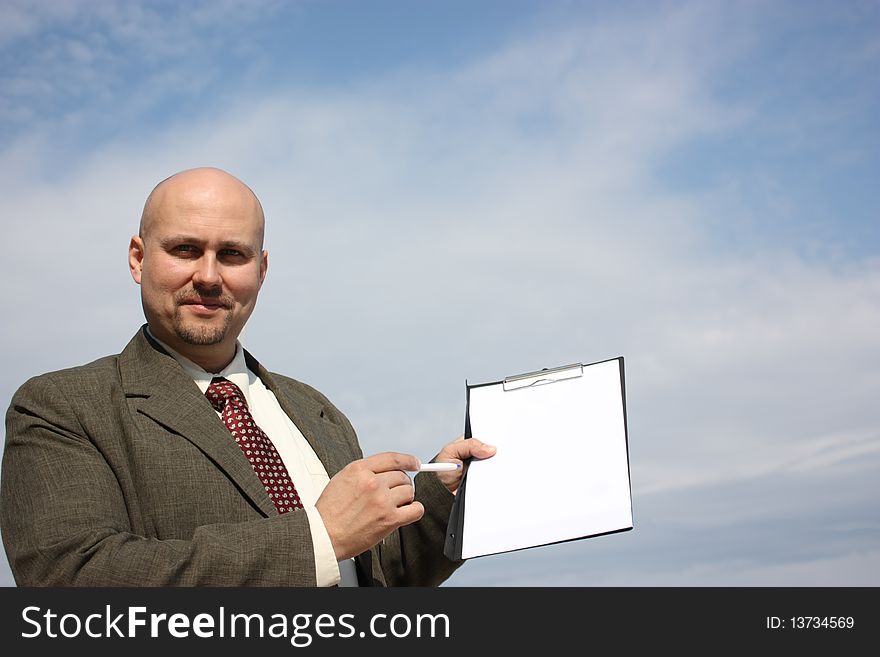 A businessman pointing a checklist on the camera isolated on a sky. A businessman pointing a checklist on the camera isolated on a sky