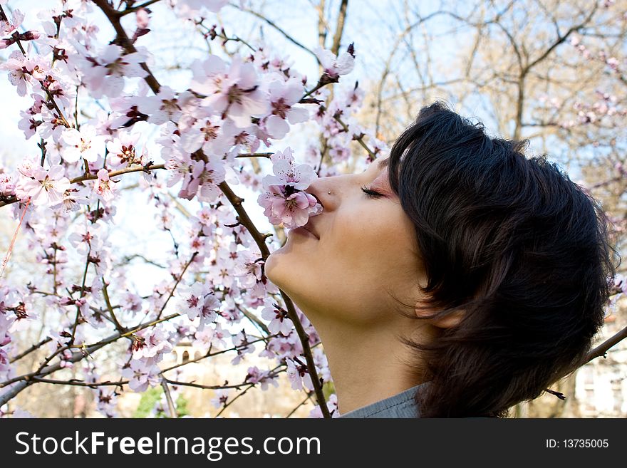 Young girl smelling the blossomming flowers of a tree. Young girl smelling the blossomming flowers of a tree