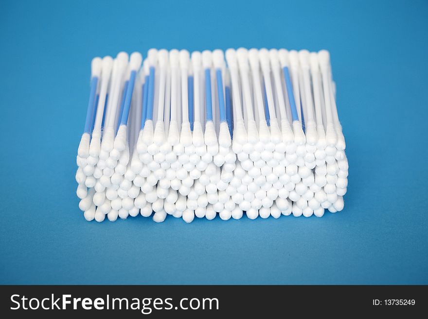 Stack of cotton swabs on blue background