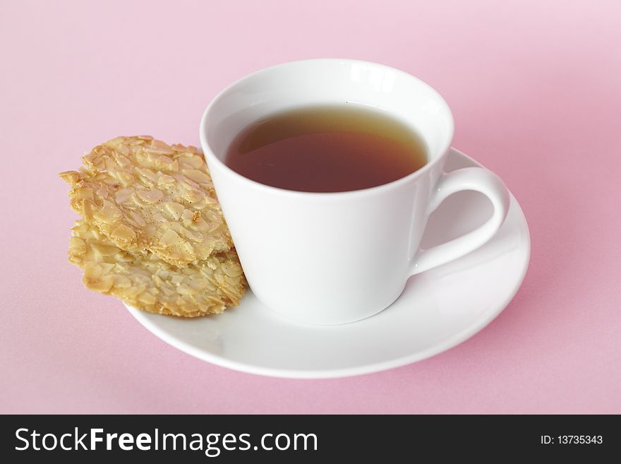 Cup of herbal tea with almond cookies on the side and a white teacup