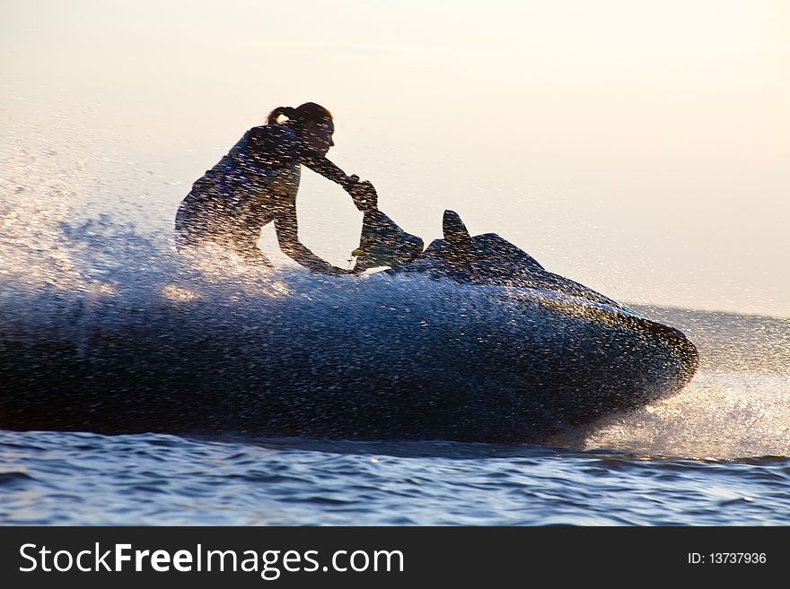 Beautiful girl riding her jet skis in the sea at sunset. silhouette