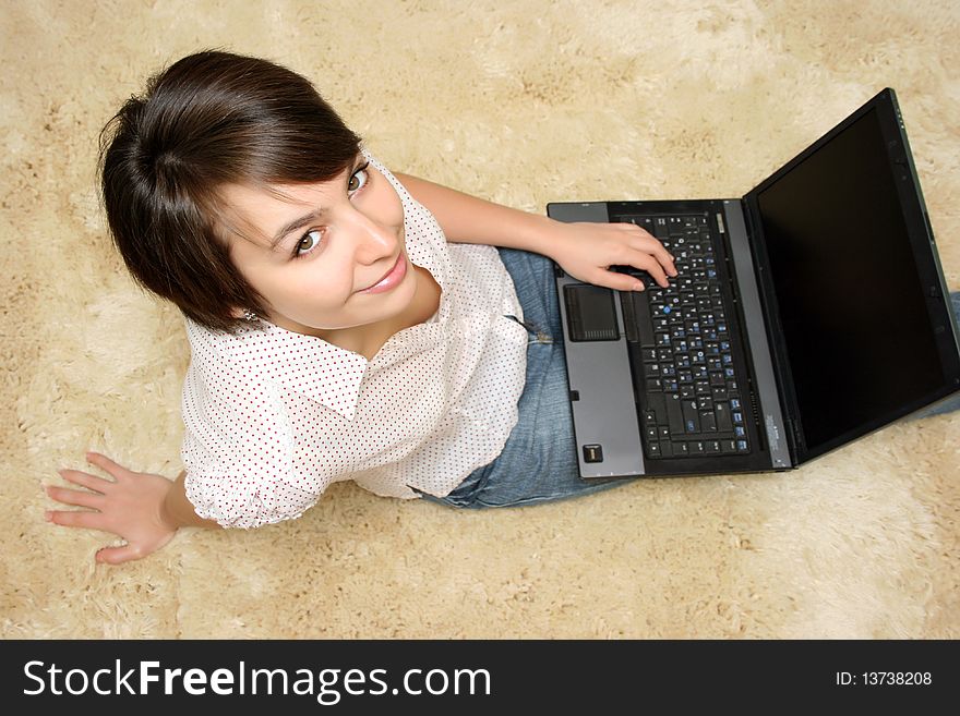 Pretty young woman sitting on the carpet with laptop. Pretty young woman sitting on the carpet with laptop