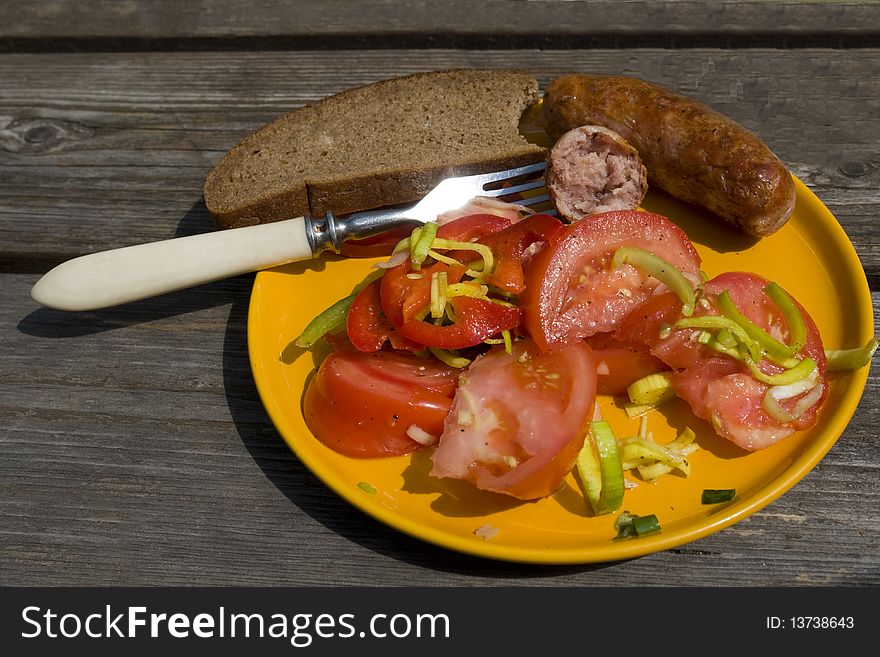 Tomato salad with sausage on the yellow plate