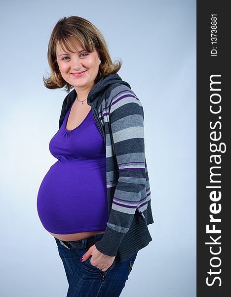 Young cute pregnant girl in a striped sweater. In studio