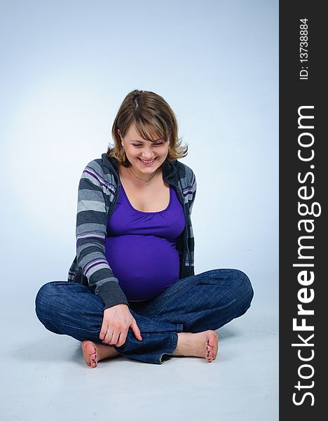 Young cute pregnant girl in a striped sweater. In studio