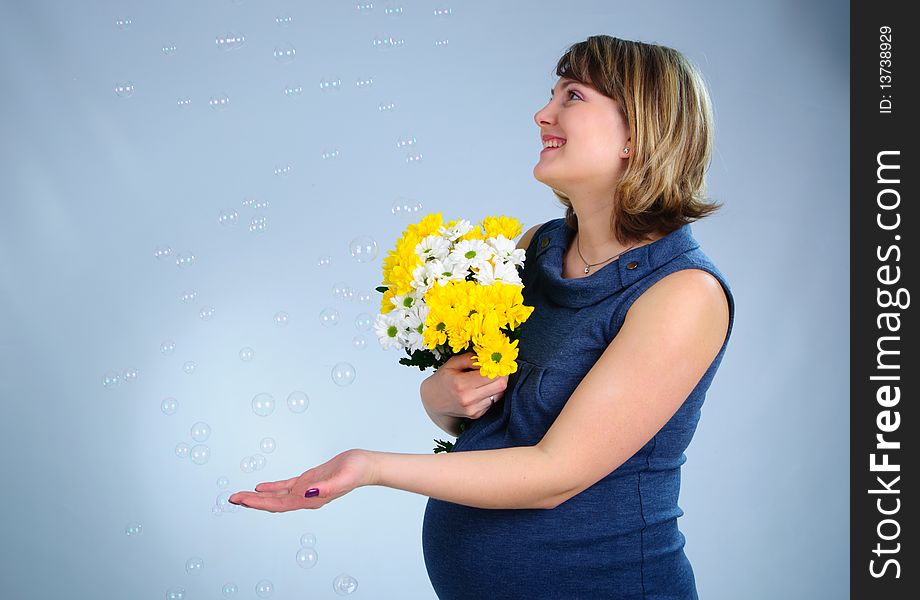 Young cute pregnant girl in a blue dress. In studio
