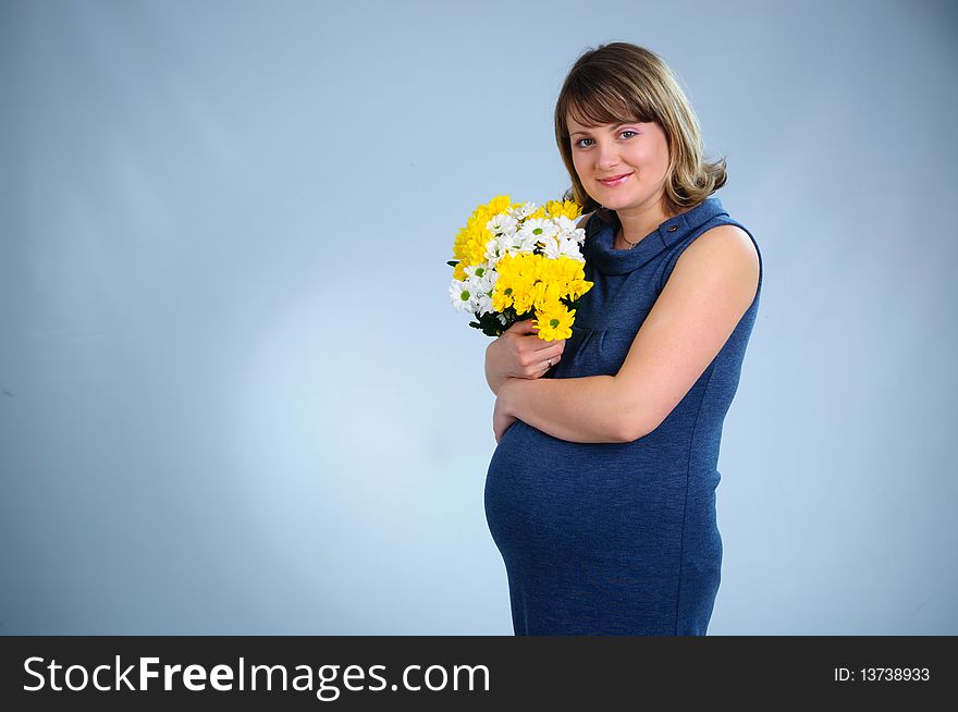 Young cute pregnant girl with bouquet of flowers