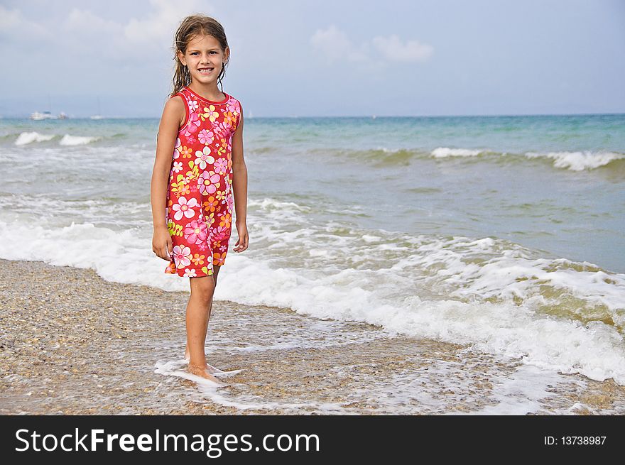 Sweet beautiful girl in a bright dress looks on the sea. Sweet beautiful girl in a bright dress looks on the sea