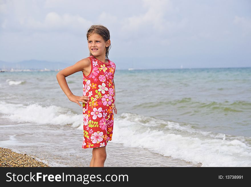 Sweet beautiful girl in a bright dress looks on the sea. Sweet beautiful girl in a bright dress looks on the sea