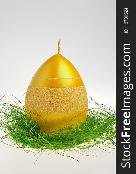 Yellow egg shaped candle on green decoration isolated over white background. Yellow egg shaped candle on green decoration isolated over white background.