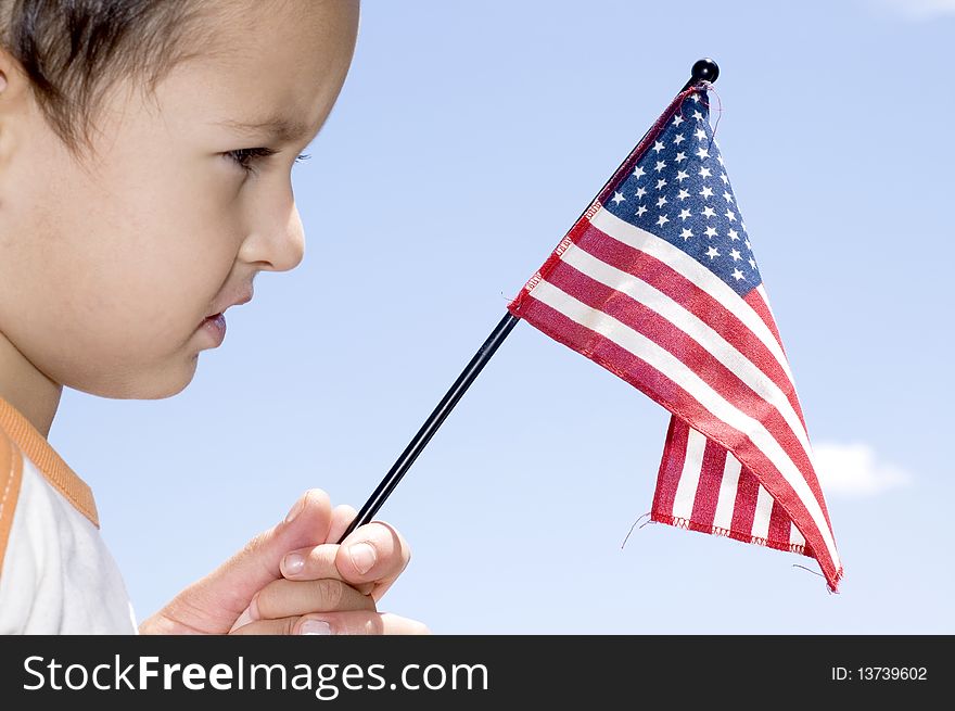 Boy holding American Flag for the independence day
(Against blue sky). Boy holding American Flag for the independence day
(Against blue sky)