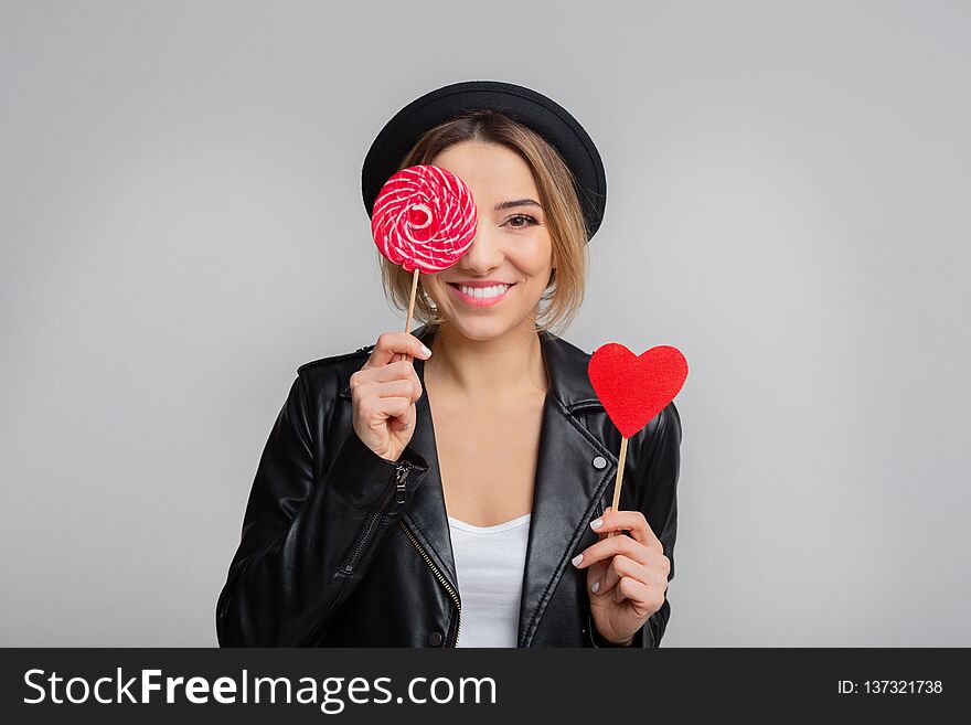 Joyful woman with lollipop and paper heart, having fun