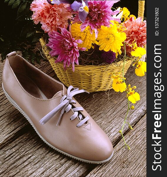 Tan shoe on wooden background with flowers. Tan shoe on wooden background with flowers