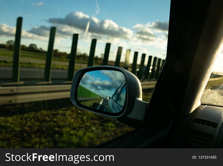 View of the highway in the rear-view mirror, in the background of the sunset. View of the highway in the rear-view mirror, in the background of the sunset