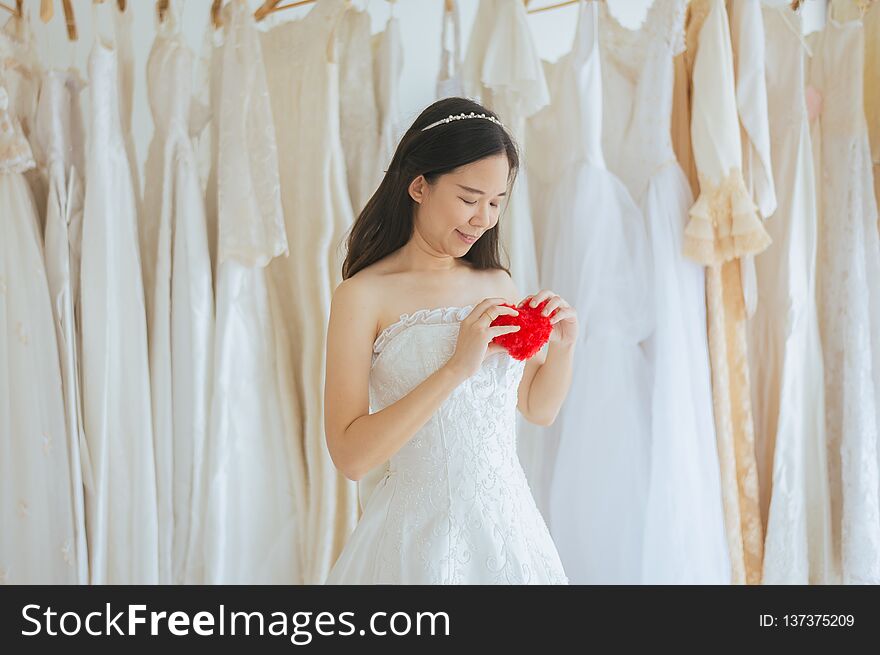 Happy young beautiful bride asian woman smiling and hand holding model red heart