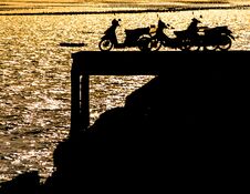 Silhouette Of Motorcycles On Dock With Effect Of Sunset Light On Sea Stock Image