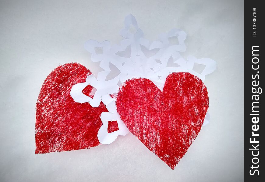 Two red hearts with white snowflake on snow