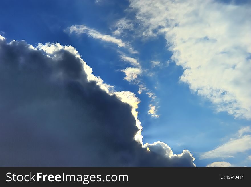 Sun covered by pretty clouds in clear blue sky, projecting remarkable colorful beams. Sun covered by pretty clouds in clear blue sky, projecting remarkable colorful beams