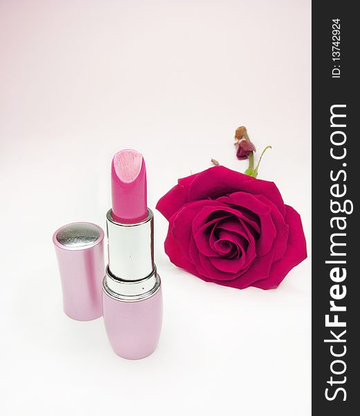 Pink lipstick in gold box with damask rose on background. Pink lipstick in gold box with damask rose on background