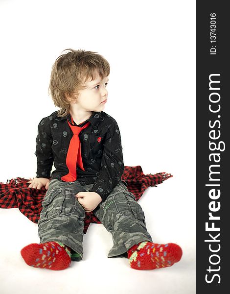 Cute child sitting on a red scarf and looking away. Cute child sitting on a red scarf and looking away