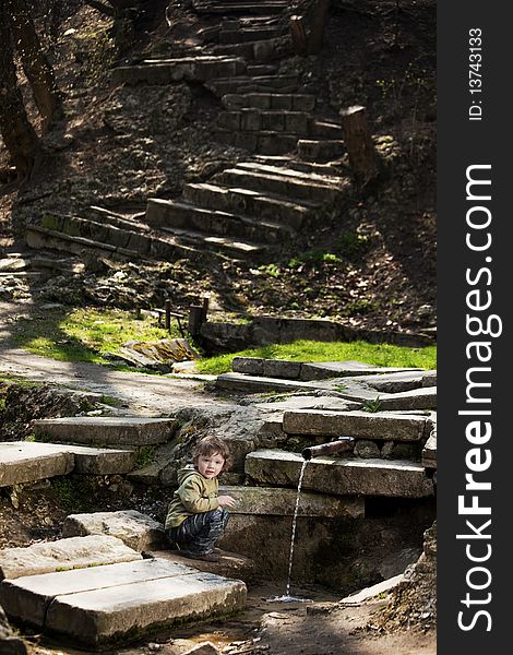 Little boy sitting near a spring