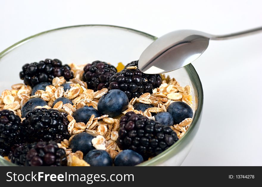 A glass bowl full of muesli, corn flakes, blackberries and blueberries. Selective focus. A glass bowl full of muesli, corn flakes, blackberries and blueberries. Selective focus.