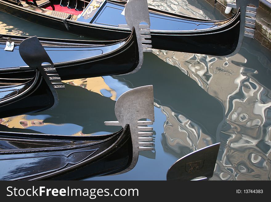 The gleaming prows of gondolas on the still surface of the canal. The gleaming prows of gondolas on the still surface of the canal