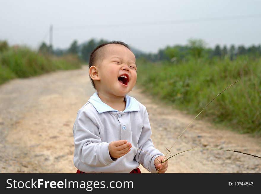 It is a laughing chinese baby on the countryside road. It is a laughing chinese baby on the countryside road.