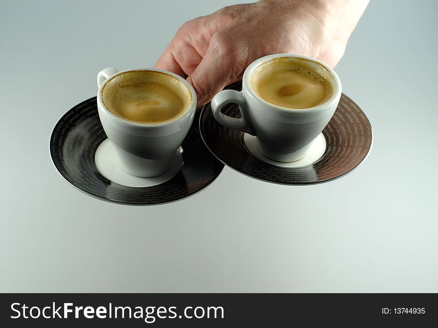 Hand serving two espresso cups