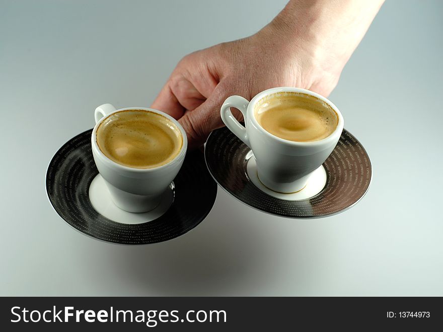 Hand serving two espresso cups