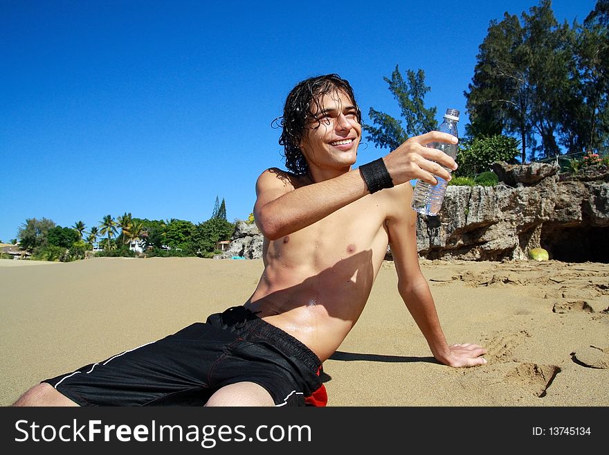 Man with bottle of  water in hand on beach