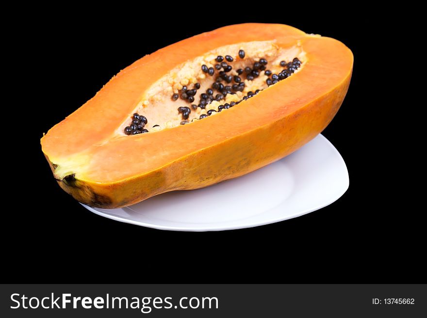 Closed-up papaya on plate isolated on black