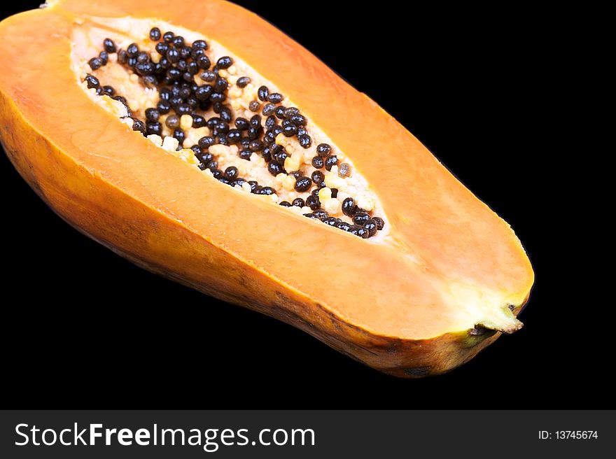 Closed-up half of papaya on black. Closed-up half of papaya on black